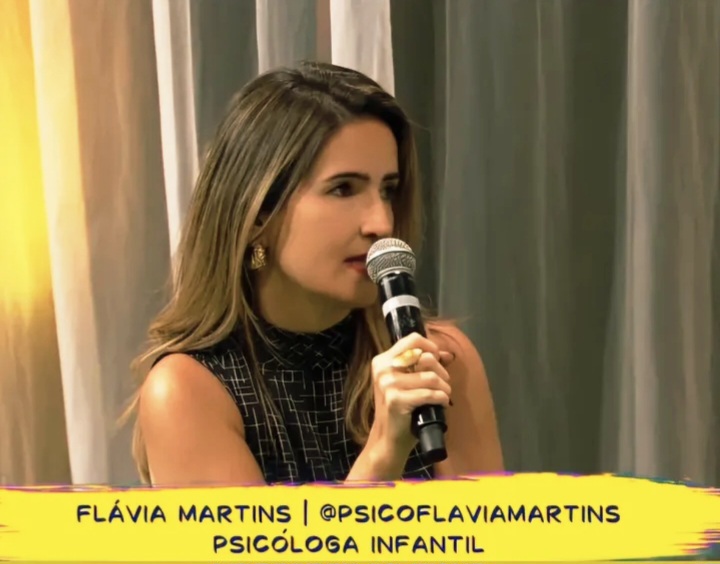 Flávia Martins falando ao microfone durante uma participação na televisão
